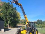 un tracteur équipé d'une fourche est garé sur un chemin de terre