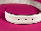 a close up of a white leather belt on a pink surface