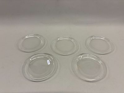 six assiettes en verre transparent posées sur un plan de travail blanc