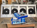 une pile de livres posée sur une table à côté d'une chaîne hi-fi