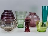 many different colored glass vases on a white surface