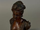 bronze bust of a woman with a flower in her hair