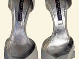 pair of women ' s silver shoes with bows on the toes