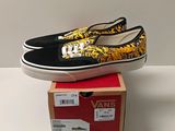 des Vans noires et jaunes sans lacets posées sur une boîte