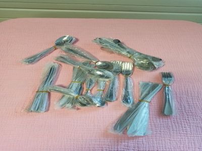 beaucoup de cuillères et de fourchettes en argent posées sur une couverture rose