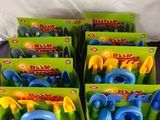 six jouets d'arrosage en plastique bleu et jaune, dans leurs boîtes, posés sur une table