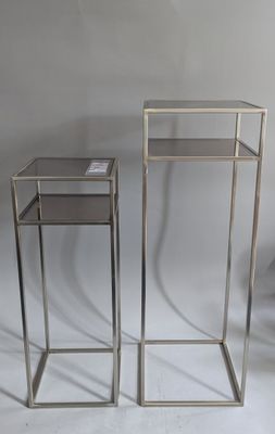 pair of silver metal nesting tables with glass tops