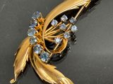 a gold brooch with blue stones on a black surface