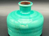 a small green vase sitting on a black surface