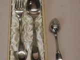 une cuillère et une fourchette en argent dans une boîte contenant une cuillère et un repose-cuillère