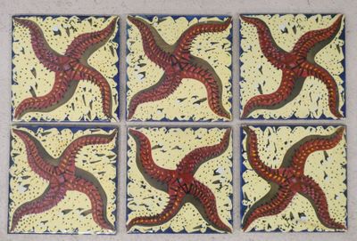 six red and yellow starfishs sitting on top of a white surface