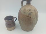 un vase marron et une tasse marron posés sur une surface blanche