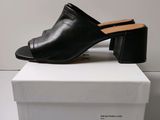 a pair of black leather mulers on top of a white box
