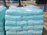 many bags of water sitting on pallets on the ground