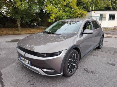 La voiture grise est garée sur le parking à côté de la maison.
