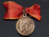 an old medal with a red ribbon around it and a silver medal with a red ribbon around it