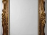 a gold framed mirror on a wall with a white background