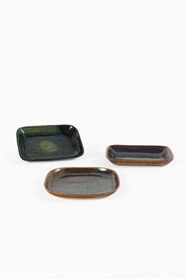 trois petites assiettes rectangulaires recouvertes d'un émail noir et marron