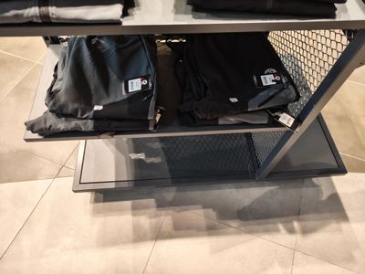 une étagère métallique sur laquelle sont posés des sacs, dans un magasin