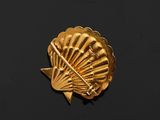 gold plated shell shaped brooch on black surface with black background