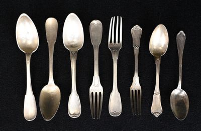 de nombreuses cuillères et fourchettes en argent sur une table noire