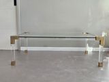 une table basse en verre avec des pieds dorés et un plateau en verre