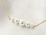 un collier de perles blanches avec une chaîne en or sur fond blanc