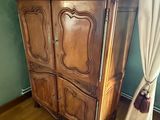 une armoire en bois dans un coin de la pièce, à côté d'une chaise