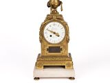 une image représentant une horloge en or surmontée d'un oiseau