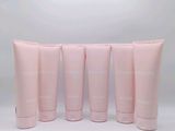 four tubes of pink lotion sitting next to each other on a white surface
