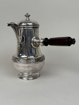 an antique silver coffee pot with a wooden handle on a white surface
