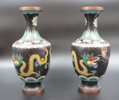 pair of asian vases with dragon designs on them on a black surface