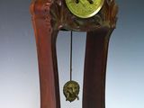 une horloge en bois avec un cadran vert, posée sur un socle