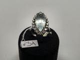 une bague ovale sertie d'une aigue-marine et de diamants, posée sur un socle noir