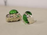 pair of green glass and silver plated earrings on a white surface