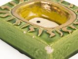 a green square shaped candle holder with a smiley face in the center