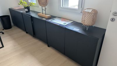 un meuble noir surmonté d'une lampe, dans une pièce