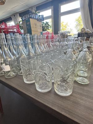 des bouteilles et des verres posés sur une table dans un magasin, avec une vitrine en arrière-plan
