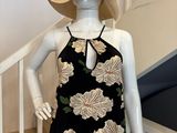 Le mannequin porte une robe à fleurs noire et blanche et un chapeau de paille.