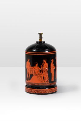 an orange and black vase sitting on top of a white table