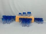 des verres à shot en verre bleu et un support en bois sur fond blanc