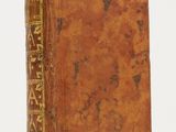an old book with writing on it sitting on a white surface