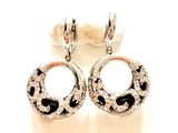 une paire de boucles d'oreilles ornées de pierres noires et blanches sur un fond blanc