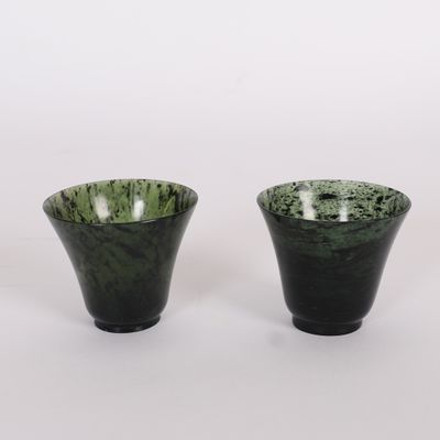 une paire de vases noirs et verts posés sur une surface blanche