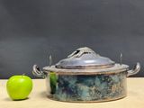 a green apple sitting next to a metal pot on a table