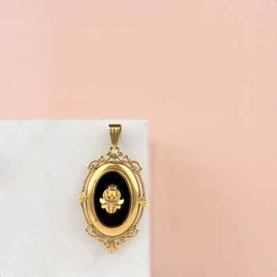 a gold locke with a black and white cameo on it