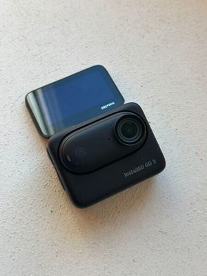 un petit appareil photo posé sur la table, à côté d'un téléphone portable