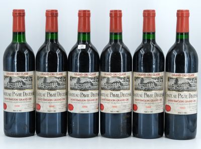 six bottles of red wine lined up on a white surface