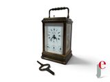 une petite horloge avec une clé à côté, posée sur une surface blanche