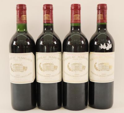quatre bouteilles de vin sont alignées sur une surface blanche